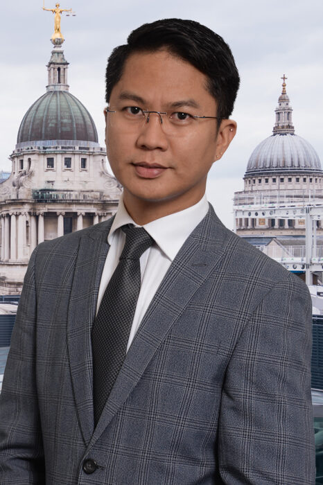 A professional corporate headshot with a London background.